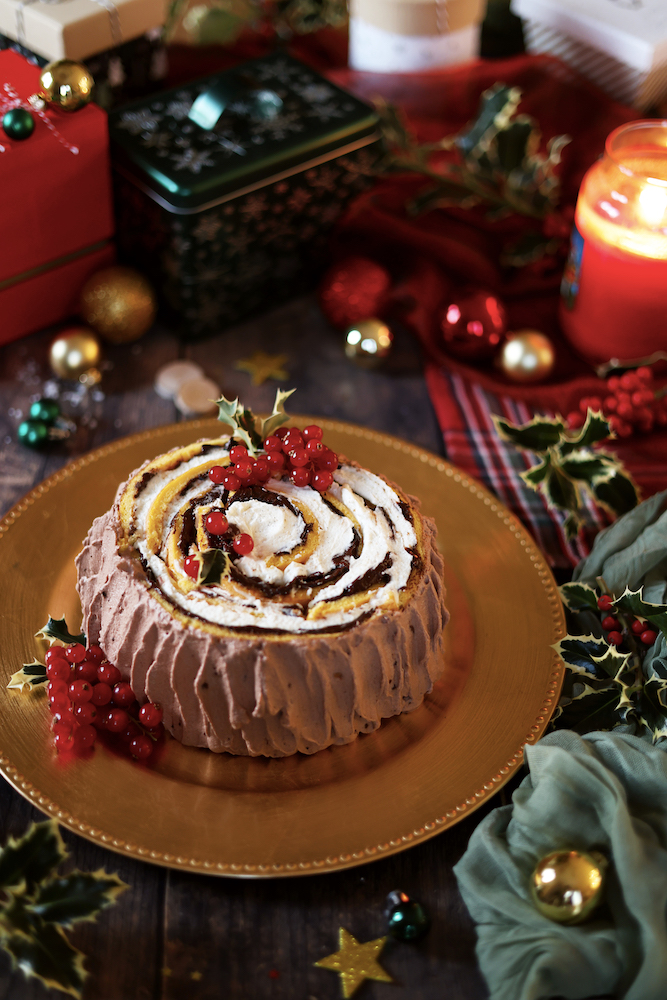 Torta tronchetto di natale servito su un piatto dorato in una tavola con addobbi natalizi