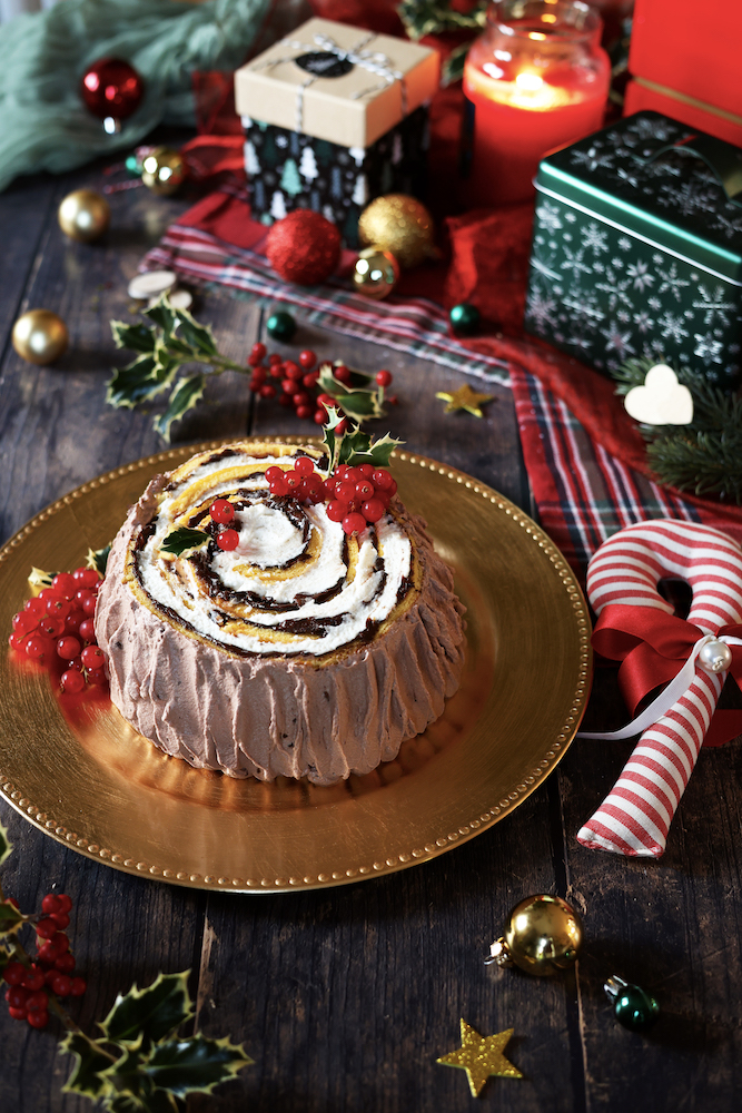Torta tronchetto di Natale su un piatto dorato in una tavola con addobbi natalizi