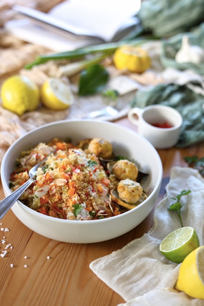 Close up del cous cous alle verdure con polpette di tacchino al limone servito su una bowl bianca con cucchiaio