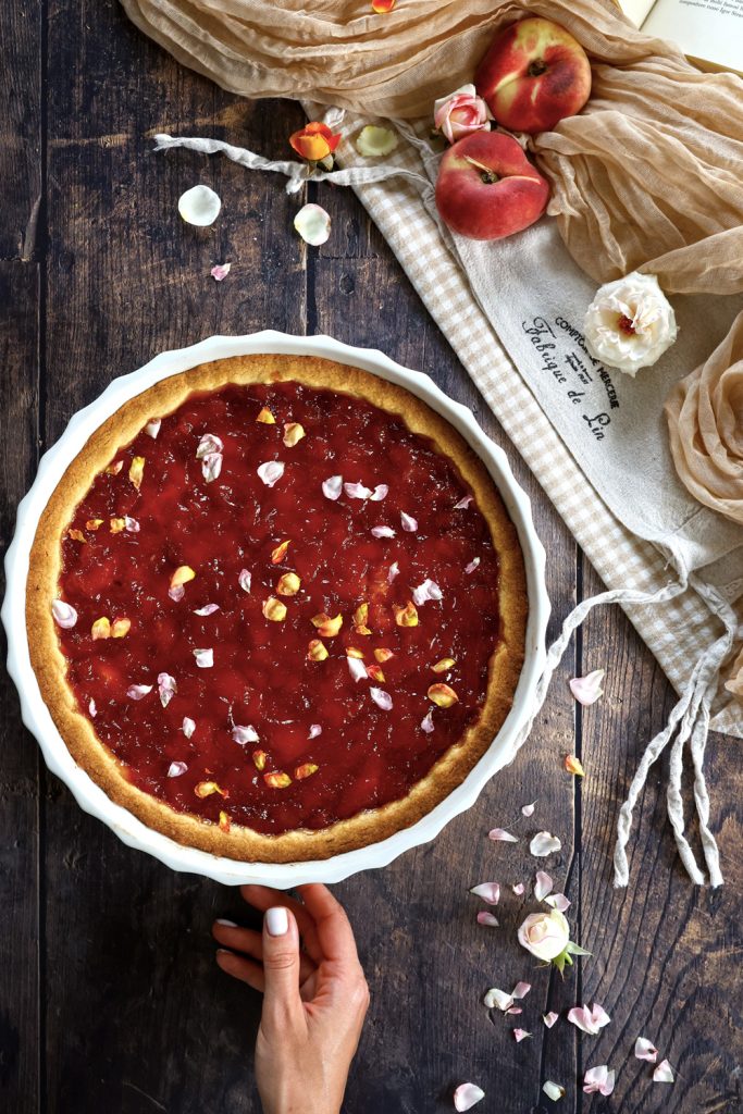 Vista dall'alto della crostata con composta di pesche e petali di rose